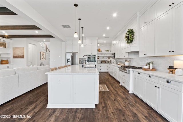 kitchen featuring appliances with stainless steel finishes, a center island with sink, and white cabinets