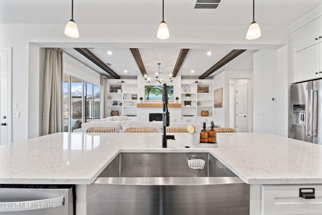 kitchen featuring stainless steel appliances, light stone countertops, hanging light fixtures, and white cabinets