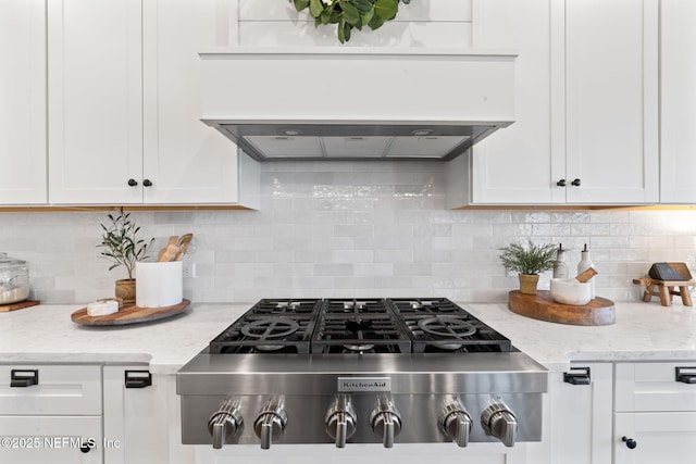 kitchen featuring premium range hood, stainless steel gas cooktop, white cabinets, and light stone counters