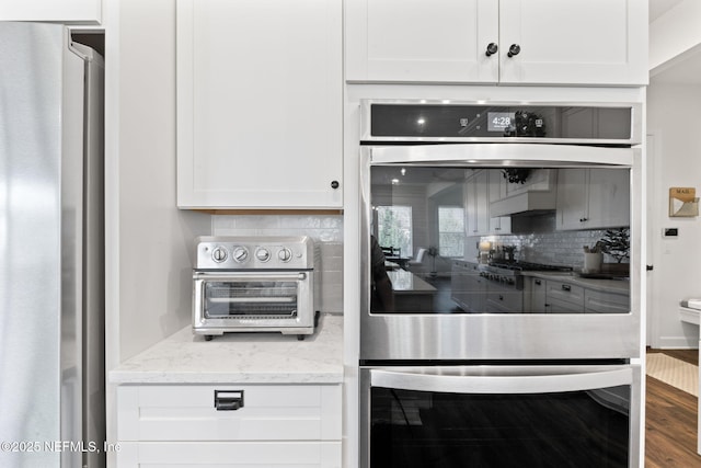 kitchen with white cabinetry, decorative backsplash, stainless steel appliances, and light stone counters