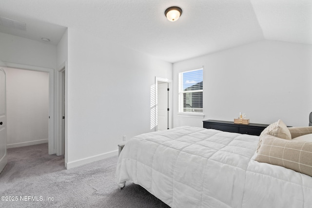 bedroom with lofted ceiling, light colored carpet, and a textured ceiling