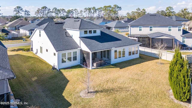 rear view of property featuring a yard and a sunroom