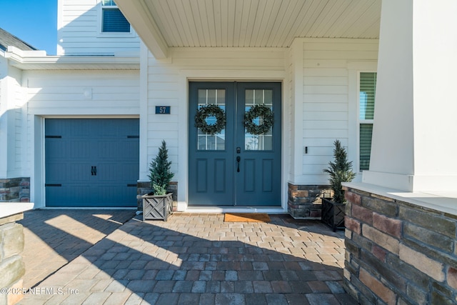 view of exterior entry with a garage and french doors