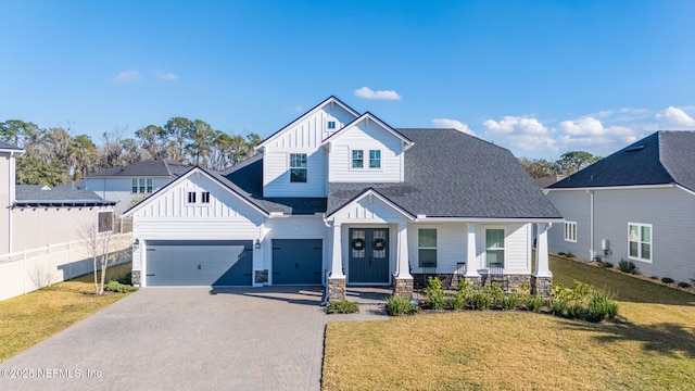 view of front of home with a garage, covered porch, and a front lawn