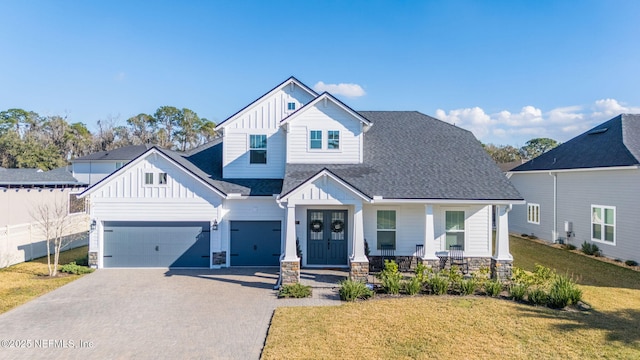 view of front of house with a garage, a front yard, covered porch, and french doors