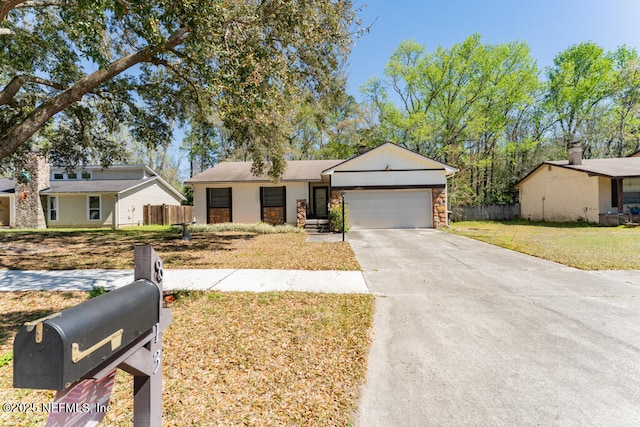 view of front of home with fence, driveway, an attached garage, a front lawn, and stone siding