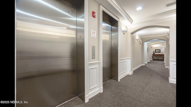 corridor with ornamental molding, elevator, and dark colored carpet