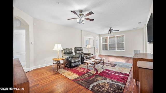 living room featuring ceiling fan, hardwood / wood-style floors, and a textured ceiling