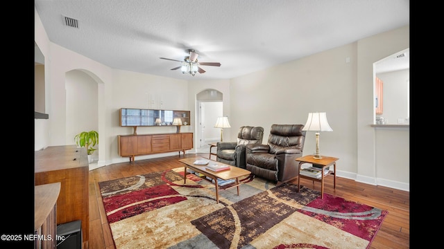 living room featuring hardwood / wood-style flooring, ceiling fan, and a textured ceiling