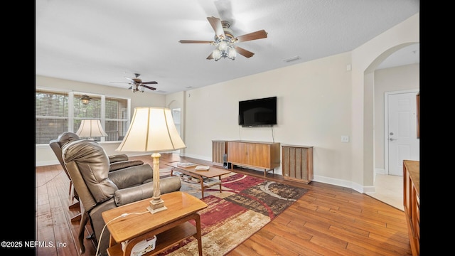 living room with ceiling fan, light hardwood / wood-style floors, and a textured ceiling