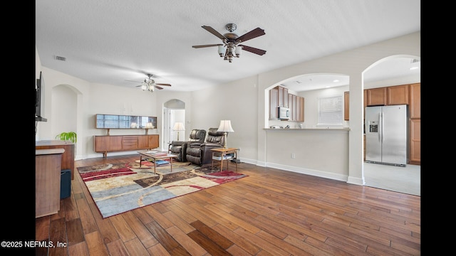 living room featuring hardwood / wood-style flooring, ceiling fan, and a textured ceiling