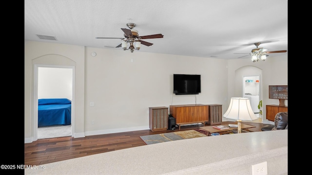 living room with washer / dryer, dark hardwood / wood-style floors, and ceiling fan