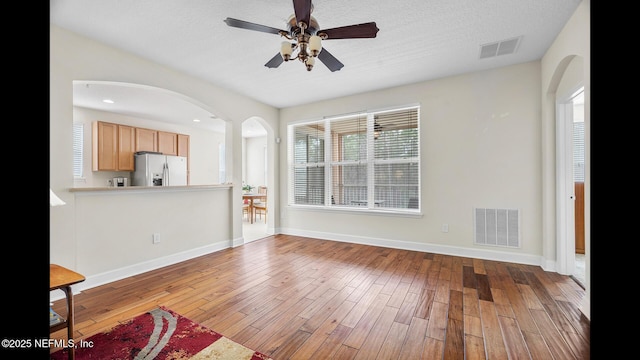 unfurnished living room featuring ceiling fan, light hardwood / wood-style floors, and a textured ceiling