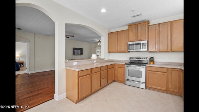 kitchen with ceiling fan, stainless steel appliances, and a textured ceiling