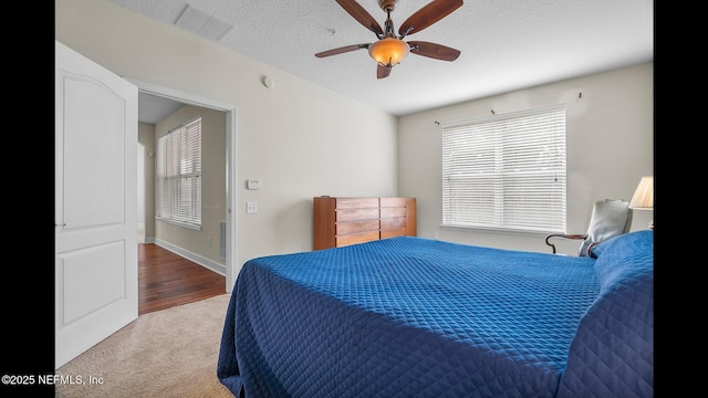 carpeted bedroom with ceiling fan and a textured ceiling