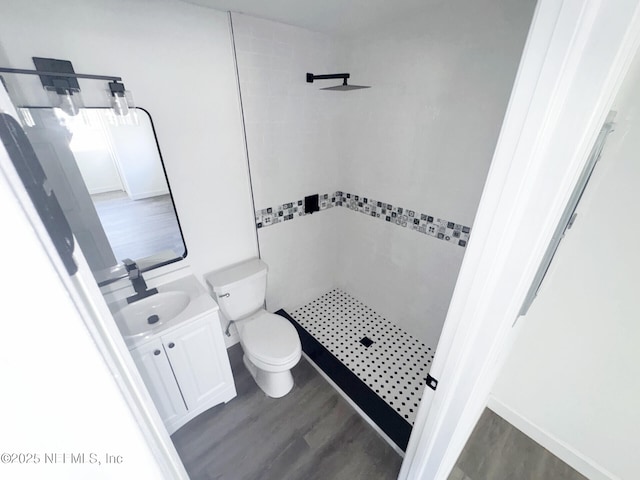 bathroom with vanity, hardwood / wood-style flooring, toilet, and tiled shower