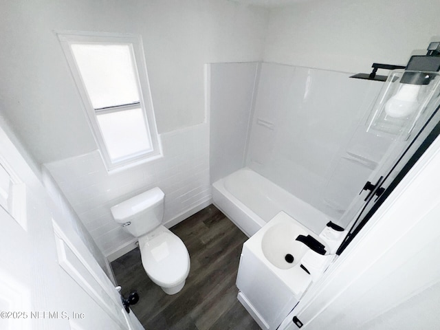 bathroom with toilet, hardwood / wood-style floors, tile walls, and a shower