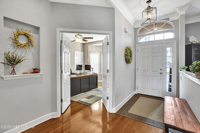 entrance foyer with a ceiling fan, baseboards, ornamental molding, and wood finished floors