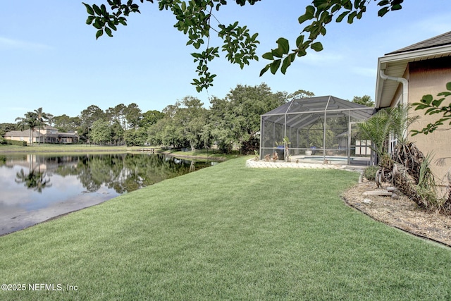 view of yard with glass enclosure, a water view, and an outdoor pool