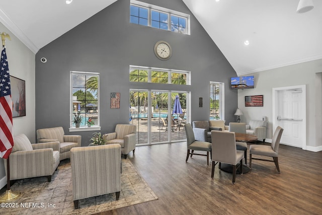 dining room featuring crown molding, baseboards, wood finished floors, and high vaulted ceiling