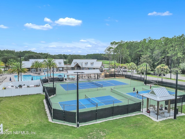 view of tennis court featuring a lawn, a community pool, and fence