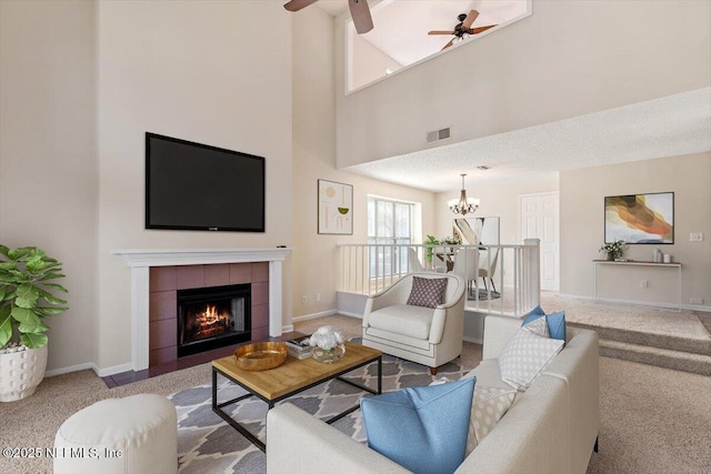 1706 Wood Hill Pl Unit 1706, Jacksonville, FL 32256 - carpeted living area featuring baseboards, visible vents, ceiling fan with notable chandelier, a fireplace, and a towering ceiling