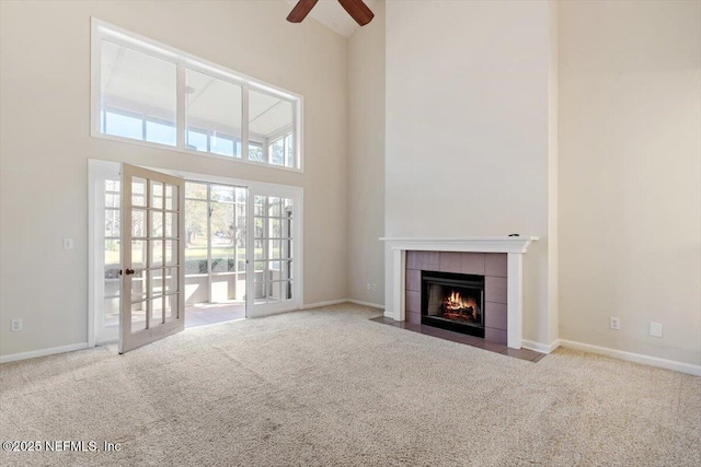 1706 Wood Hill Pl Unit 1706, Jacksonville, FL 32256 - unfurnished living room featuring a towering ceiling, baseboards, a tile fireplace, and light colored carpet