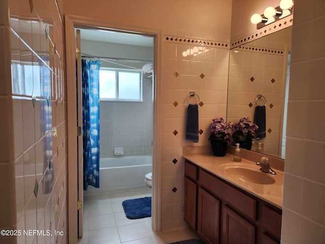 full bathroom with shower / tub combo with curtain, tile patterned floors, toilet, tile walls, and vanity