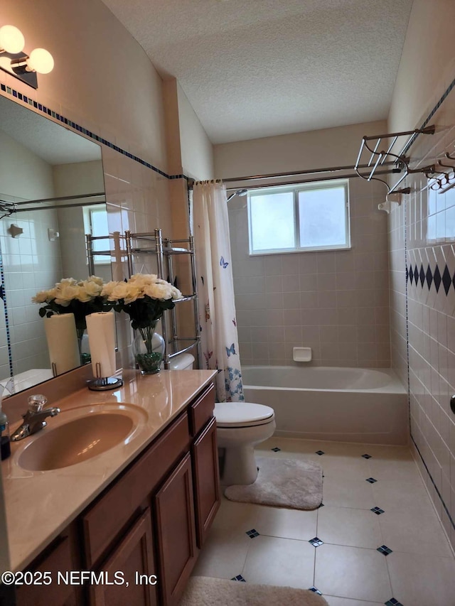 full bathroom with toilet, a textured ceiling, vanity, shower / bath combo with shower curtain, and tile patterned flooring