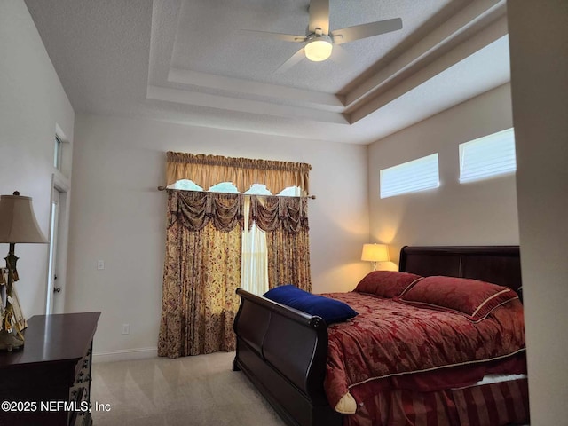 carpeted bedroom featuring a raised ceiling, ceiling fan, and a textured ceiling