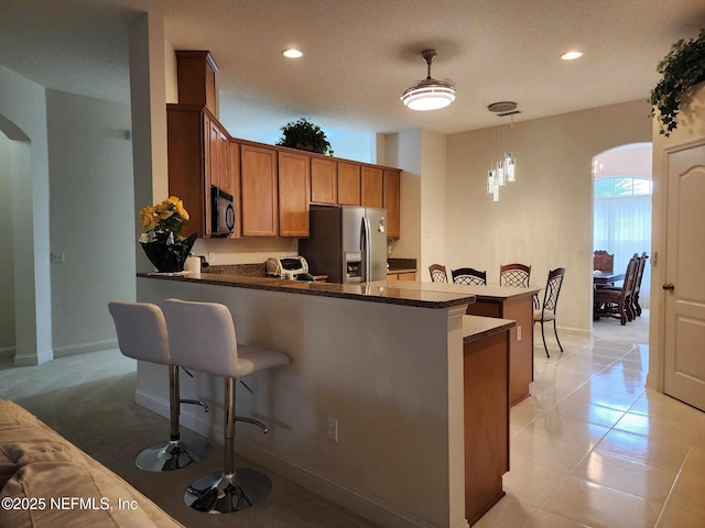 kitchen featuring decorative light fixtures, a breakfast bar area, stainless steel fridge, and kitchen peninsula