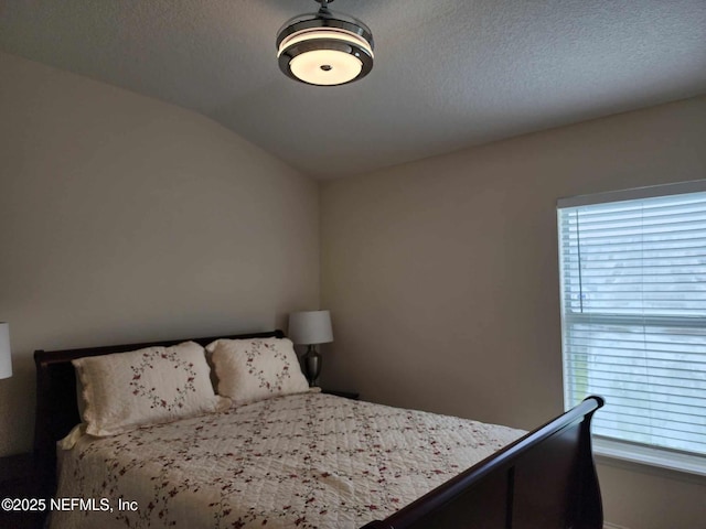 bedroom featuring multiple windows, lofted ceiling, and a textured ceiling