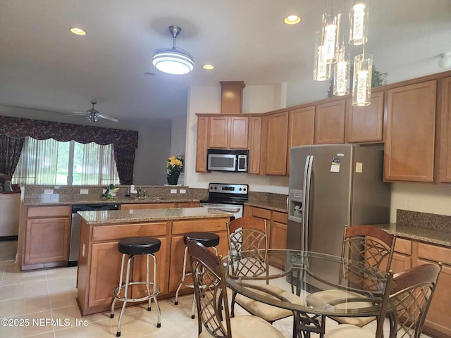 kitchen with decorative light fixtures, a center island, appliances with stainless steel finishes, kitchen peninsula, and stone counters