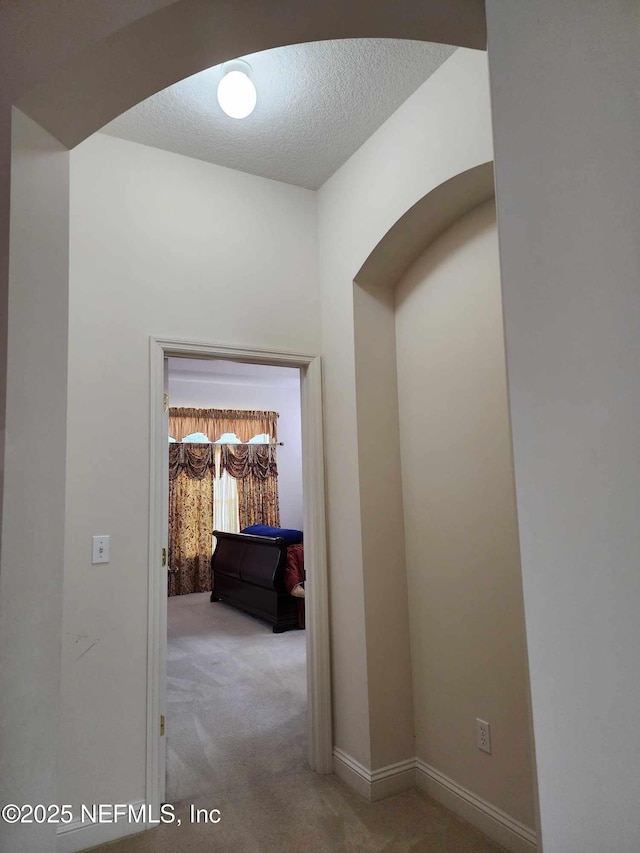 hallway featuring light carpet and a textured ceiling