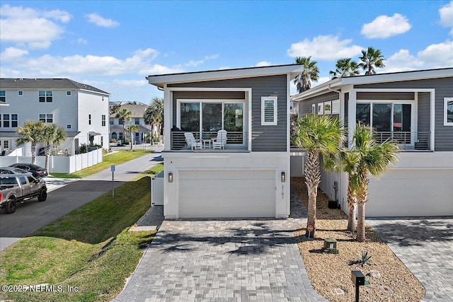 view of front of house featuring a garage, decorative driveway, and a residential view