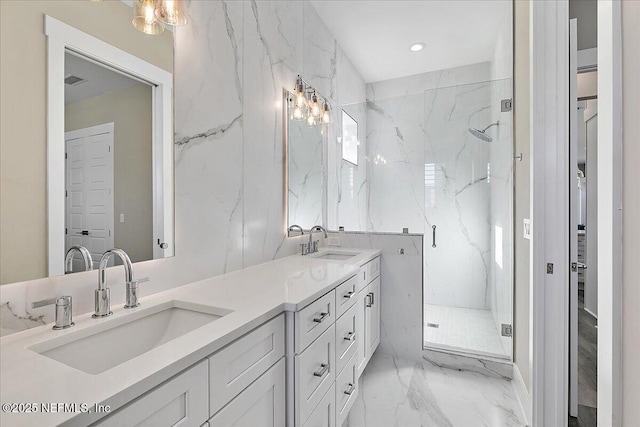 full bath with marble finish floor, a sink, a marble finish shower, and double vanity