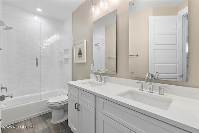 bathroom featuring enclosed tub / shower combo, a sink, toilet, and wood finished floors