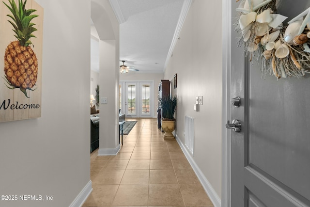 hall with light tile patterned floors, visible vents, ornamental molding, and french doors