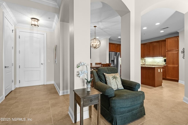 foyer featuring arched walkways, crown molding, visible vents, an inviting chandelier, and baseboards