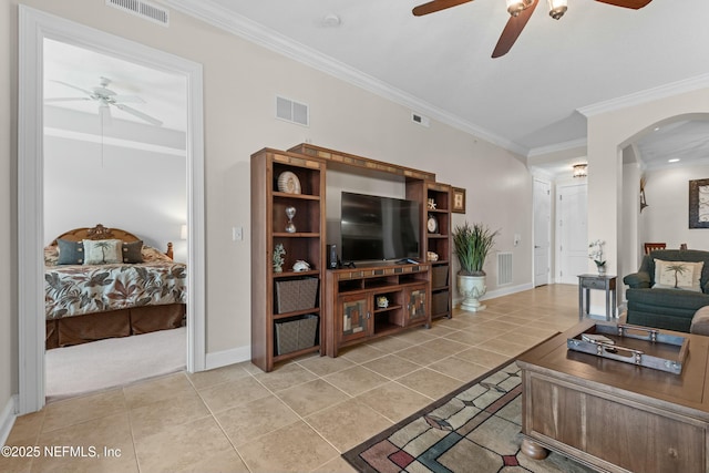 living area featuring arched walkways, light tile patterned floors, visible vents, and crown molding