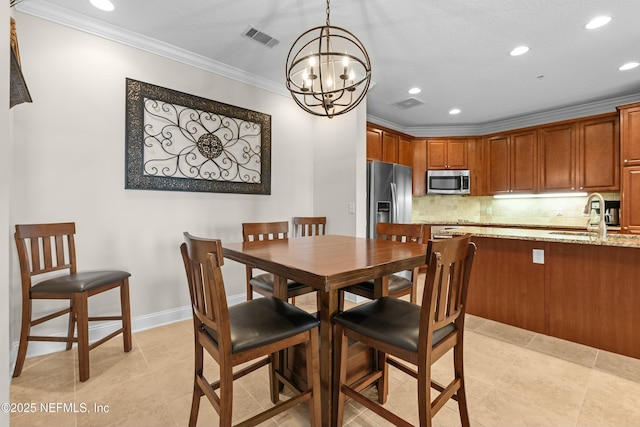 dining room with a chandelier, visible vents, crown molding, and baseboards