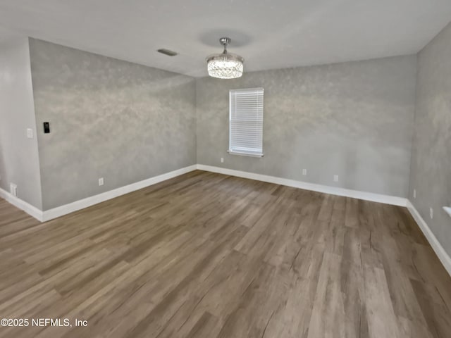 spare room featuring hardwood / wood-style flooring and a chandelier