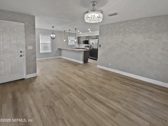 unfurnished living room featuring sink, hardwood / wood-style floors, and an inviting chandelier