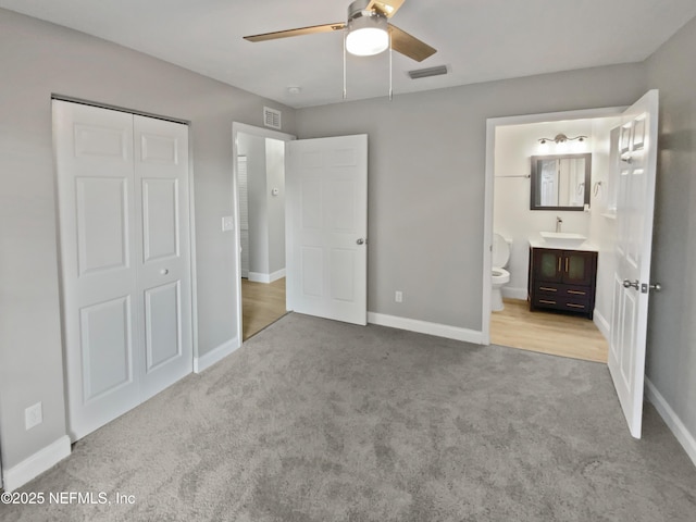 unfurnished bedroom featuring sink, ceiling fan, light carpet, ensuite bath, and a closet