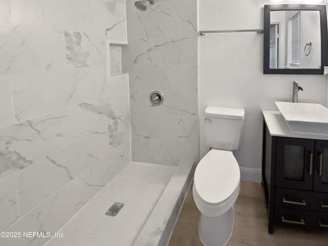 bathroom featuring vanity, toilet, and a tile shower