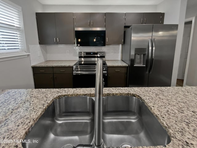 kitchen featuring backsplash, stainless steel appliances, sink, and light stone countertops