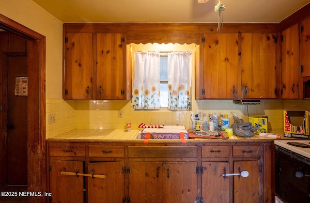 kitchen featuring tasteful backsplash, tile counters, and white range with electric cooktop