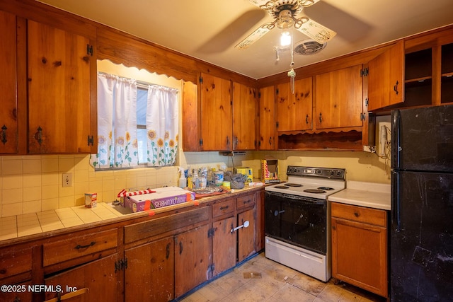 kitchen featuring white electric range, tasteful backsplash, tile countertops, black refrigerator, and ceiling fan