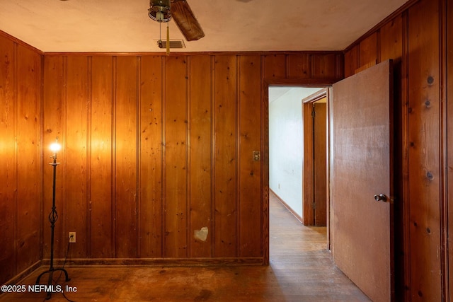 hallway featuring light wood-type flooring and wood walls