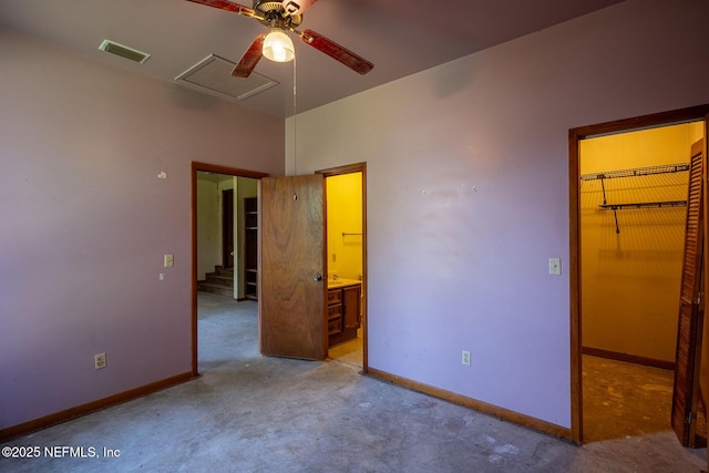 unfurnished bedroom featuring a closet, connected bathroom, concrete floors, and a walk in closet